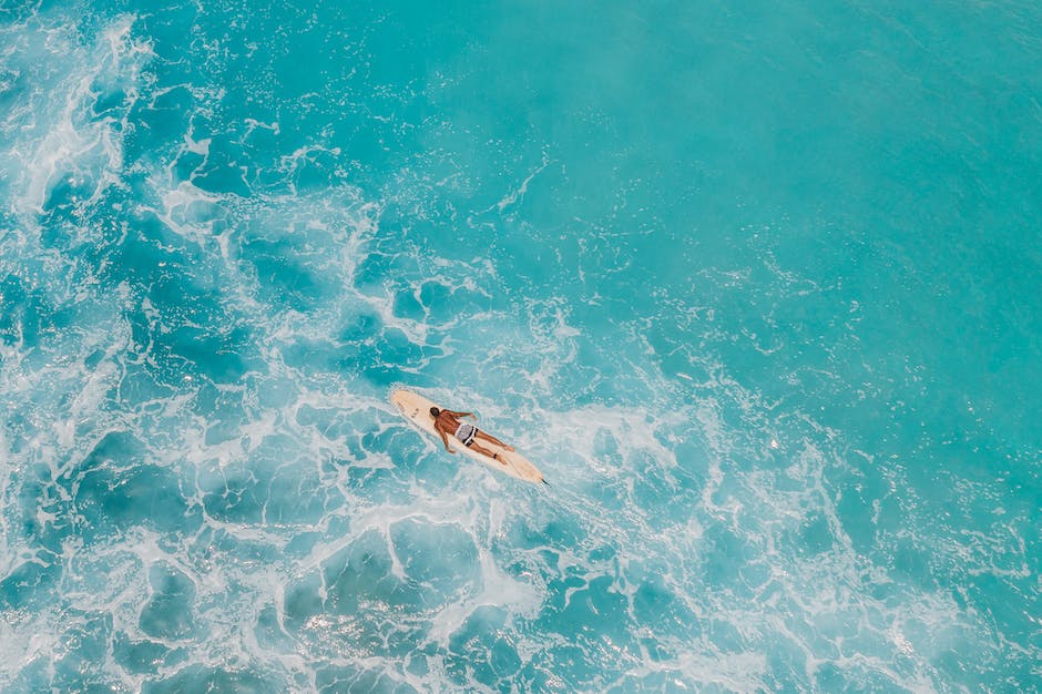 A person paddling on a prone paddleboard in a serene lake surrounded by nature.