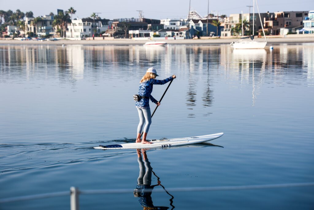 Older woman paddleboarding in calm marina waters